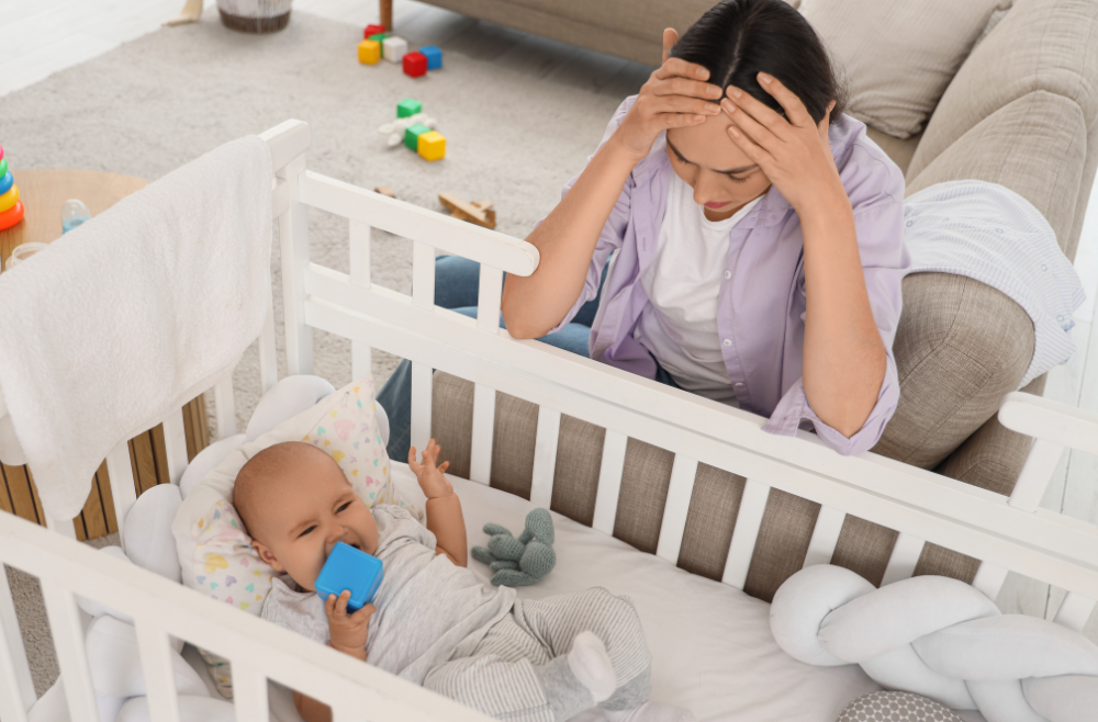 frustrated mother beside the crib with baby