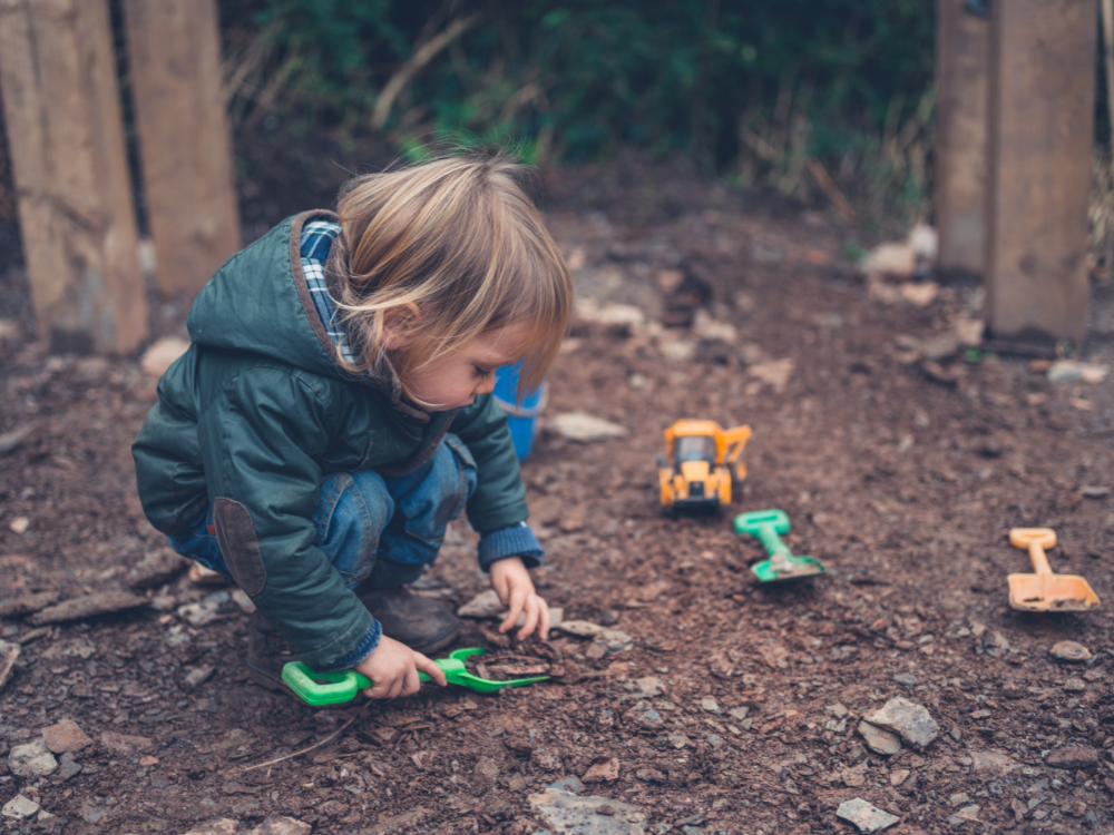toddler playing outdoors with dirt