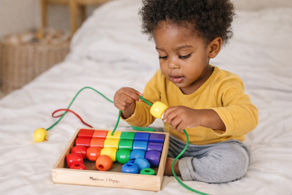 2 year old playing with threading beads toy
