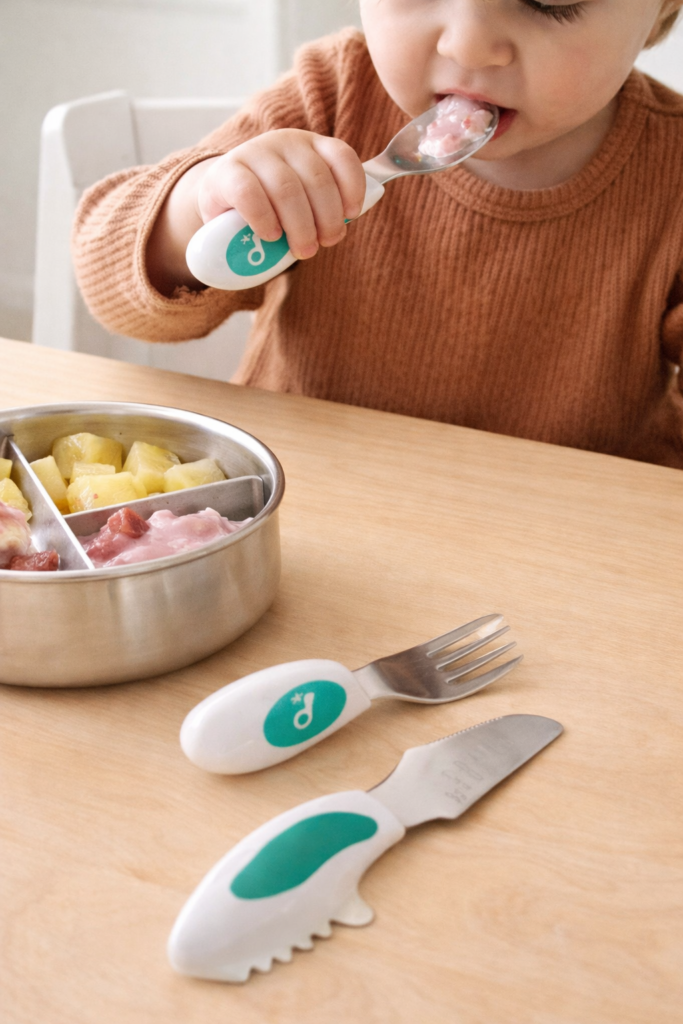 toddler eating food with a spoon