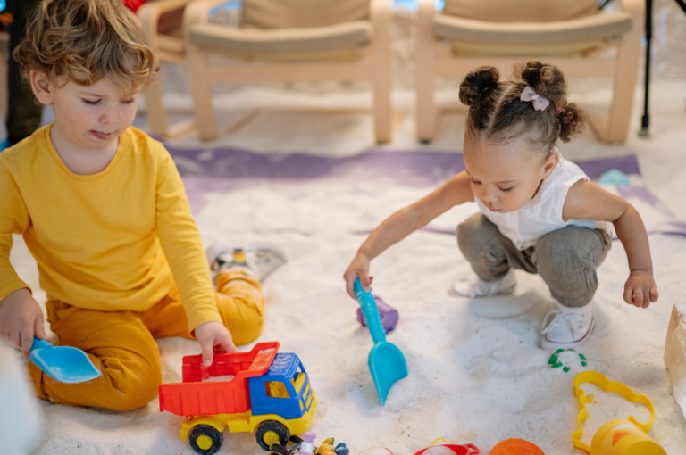 two toddlers playing in sandpit
