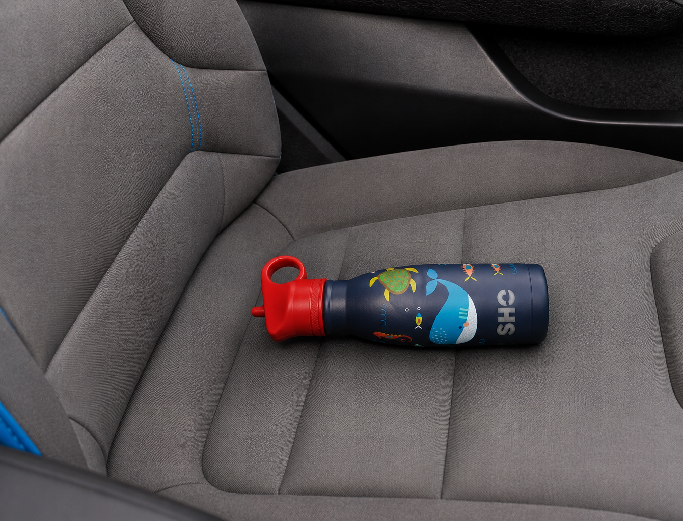 SHO kids water bottle lying on its side on a car seat.