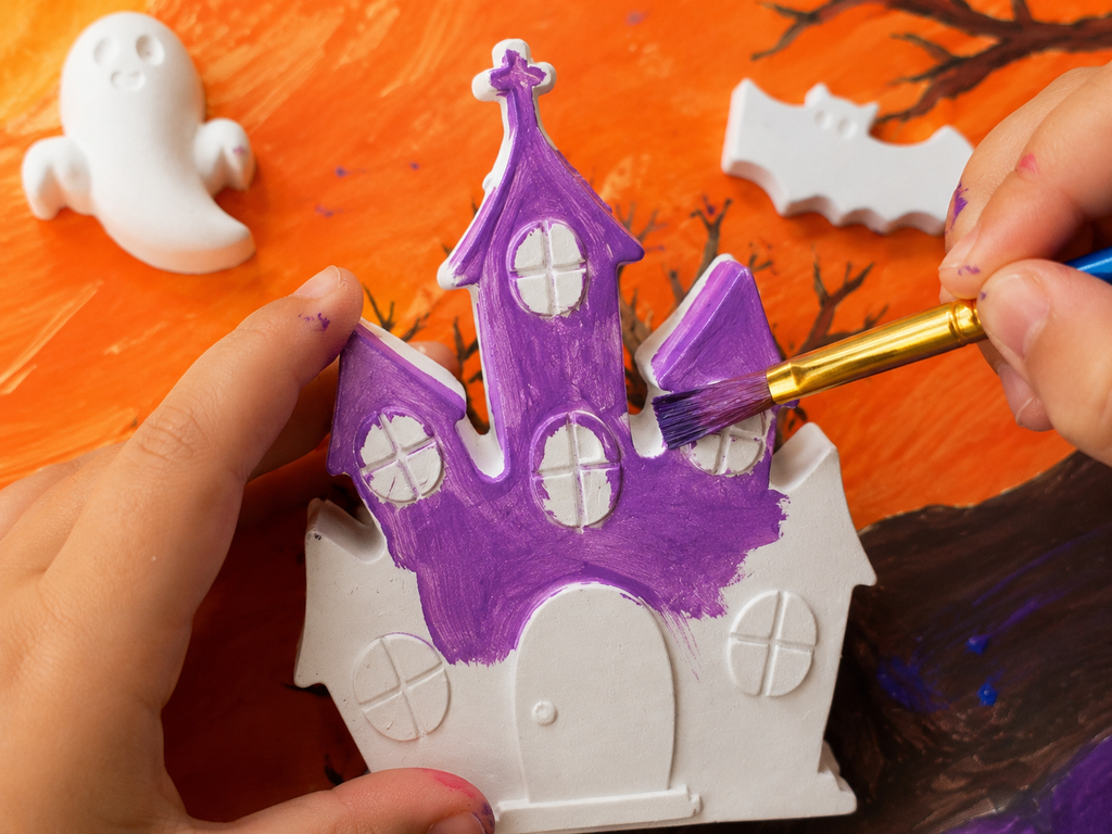 Halloween Plaster Painting activity. Here a castle is being painted in purple.