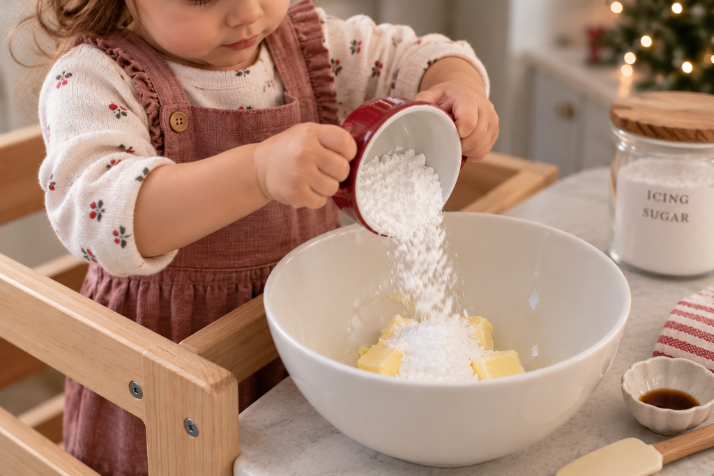 Toddler adding icing sugar to butter for a simple Christmas cookie recipe.
